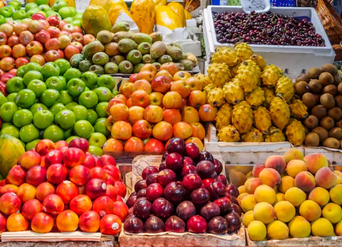Banco di frutta fresca con mele, pesche, prugne e kiwi